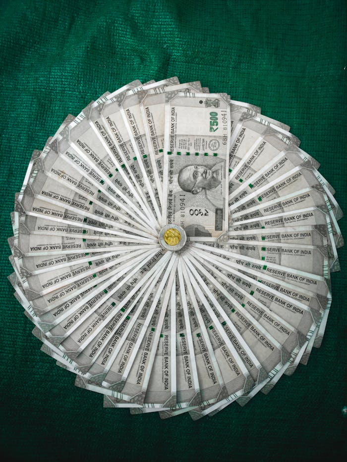 Top view of Indian Rupee notes arranged in a circular pattern on a green surface.